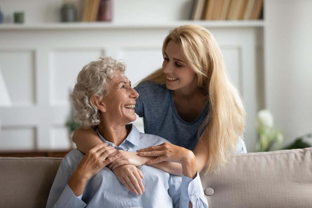 Una mujer joven sonriendo junto a una mujer mayor.